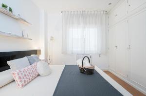 a white bedroom with a bed with a basket on it at Apartamento BS Oviedo Centro in Oviedo