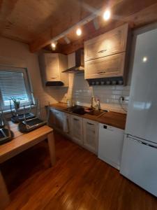 een keuken met houten kasten en een witte koelkast bij Agroturystyka Kluki u Tosi in Smołdzino