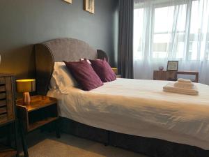 a bedroom with a bed with purple pillows and a window at Rooms at The March Hare in Market Rasen