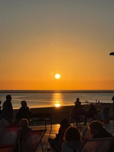 a group of people sitting on the beach watching the sunset at Sternschnuppe in Borkum