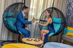 un uomo e una donna seduti sulle sedie con da bere di Hotel Pejo a Peio Fonti