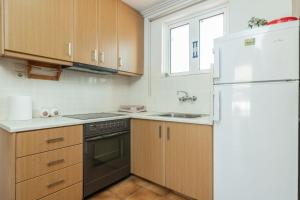 uma cozinha com armários de madeira e um frigorífico branco em Natasas Apartments em Alykes