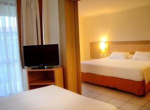 ein Hotelzimmer mit zwei Betten und einem Flachbildfernseher in der Unterkunft Flat no Beach Class Resort in Porto De Galinhas
