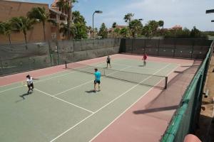 a group of people playing tennis on a tennis court at All Inclusive - Divi Village Golf and Beach Resort in Palm-Eagle Beach