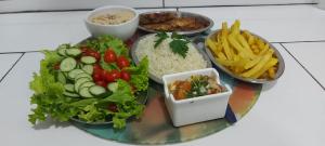 a plate of food with vegetables and rice and french fries at Pousada 2 Baioco in Paty do Alferes