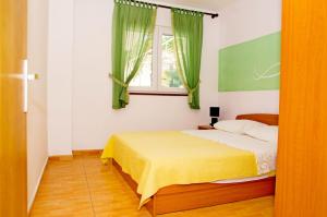 Un dormitorio con una cama con cortinas verdes y una ventana. en Apartments Mara, en Klek