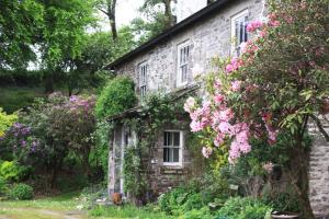 een oud stenen huis met roze bloemen bij Devon Country Paradise in Tavistock