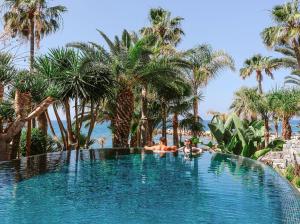 two people laying in a swimming pool with palm trees at Amathus Beach Hotel Limassol in Limassol