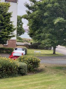 a red car parked next to a house with a tree at Pure Apartments Dunfermline East - Dalgety Bay in Saint Davids