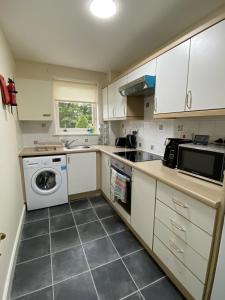 a kitchen with white cabinets and a washer and dryer at Pure Apartments Dunfermline East - Dalgety Bay in Saint Davids