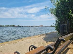 a wooden bench sitting next to a body of water at Complex Holiday Neptun in Neptun +6 photos