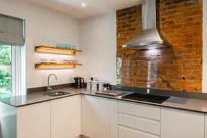 uma cozinha com armários brancos e uma parede de tijolos em South Street Apartments em Chichester