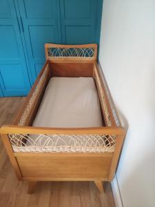 a small wooden bed in a corner of a room at maison de campagne in La Celle-Saint-Cyr