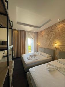 Cette chambre comprend 2 lits et une fenêtre. dans l'établissement Royal Blue Hotel, à Dhërmi