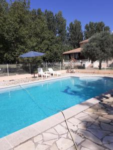 a swimming pool with two chairs and an umbrella at B&B gite d'Ayran in Saint-Quentin-la-Poterie