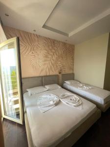 a bedroom with two beds with white sheets at Royal Blue Hotel in Dhërmi