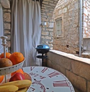 einen Tisch mit einer Obstschale neben einem Fenster in der Unterkunft House Stone house Mia casa in Stari Grad