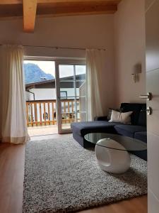 a living room with a blue couch and a glass table at Ferienhaus Kaiserblick - FEWO2 in Walchsee