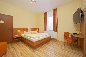 Schlafzimmer mit einem Bett, einem Schreibtisch und einem TV in der Unterkunft Hotel Reichskrone in Heidenau