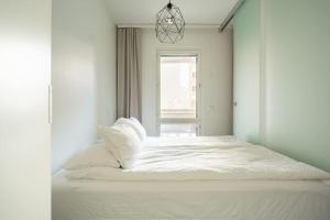 a white bed in a white room with a window at Haven Homes, Nordic Haven in Rovaniemi