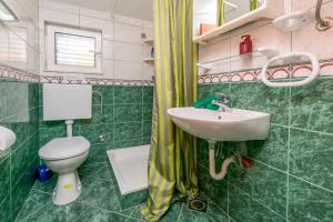 a green bathroom with a sink and a toilet at Apartments Jerko in Ražanj