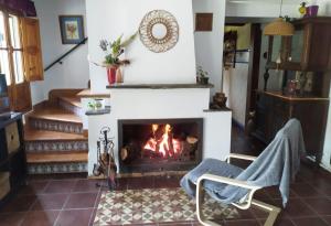 a living room with a fireplace and a chair at Alojamiento Rural La Noria in Cortegana