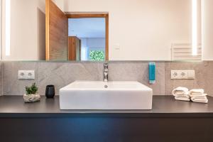 een badkamer met een witte wastafel en een spiegel bij Luisl Hof - Apartment Vinum in Cornaiano