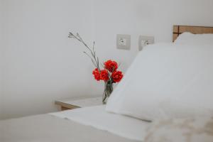 Un jarrón con flores rojas sentado en una cama en Panoramic Vlachos en Gjirokastër