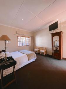 a bedroom with a bed and a flat screen tv at Ebony Lodge in Mthatha +71 photos