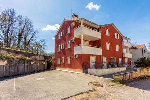 ein großes rotes Backsteingebäude mit einem Parkplatz in der Unterkunft Apartment Sally in Čižići