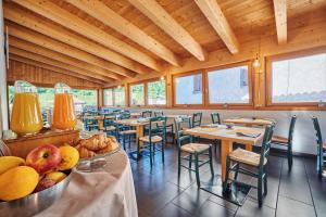 a restaurant with tables and chairs and a bowl of fruit at Hotel Bed & Bike Ledro in Molina di Ledro
