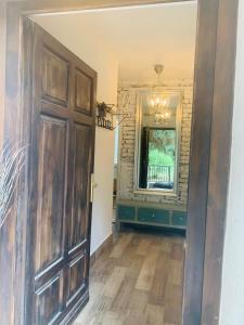 a hallway with a large wooden door and a mirror at Tūlevél/Pine-needles in Tata