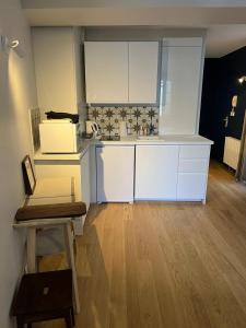 a kitchen with white cabinets and a wooden floor at So Paris Group - Fully Serviced Studio Apartment - Jardin des Plantes - Heart of Paris in Paris