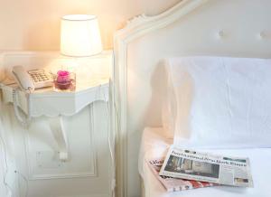 um quarto com uma cama com um telefone e uma revista em Hotel Villa Patriarca em Mirano