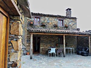 a stone house with a table and chairs outside at Casa Princesa Peralta in Lousã