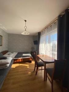 1 dormitorio con cama, mesa, cama y ventana en Twój Port, en Krynica Morska