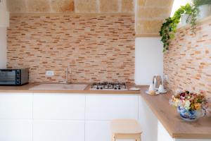 kuchnia ze zlewem i ceglaną ścianą w obiekcie La Loggia del Buon Tempo w mieście Polignano a Mare