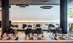 a restaurant with wooden tables and chairs and large windows at MOOONS Vienna in Vienna
