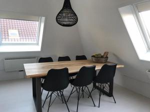 une salle à manger avec une table en bois et des chaises noires dans l'établissement Dorpsweg 18 nummer 7, à Callantsoog