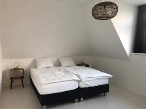 een slaapkamer met een bed met witte lakens en een lamp bij Dorpsweg 18 nummer 7 in Callantsoog