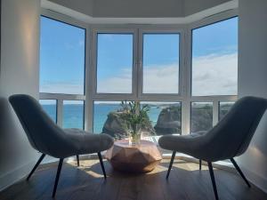2 chaises et une table devant une grande fenêtre dans l'établissement The Towan Lookout, à Newquay
