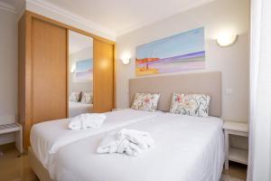 Un dormitorio con una cama blanca con toallas. en Boavista Golf & Spa - Bela Colina Village, en Lagos