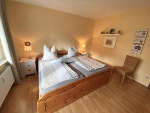 1 dormitorio con 1 cama con sábanas blancas y silla en Ferienwohnung Chris, en Braunlage
