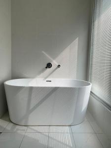 a white tub in a white bathroom with a window at Yama no Shita Homestay in Zhongpu