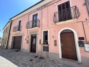 - un bâtiment rose avec deux portes et un balcon dans l'établissement Terra del Sasso Suites - Free Wifi e Netflix, à Sasso di Castalda