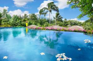 a swimming pool at a resort with palm trees and flowers at Montage Kapalua Bay in Kapalua