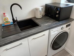 a kitchen with a microwave and a washing machine at Luxury Apartment Private House and Parking Netflix in Tartu