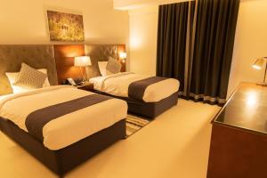 um quarto de hotel com duas camas e uma janela em Tulip Inn Majan Hotel em Salalah