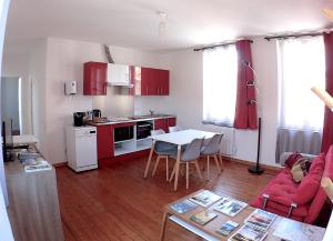 ein Wohnzimmer mit einem Tisch und eine Küche mit roten Schränken in der Unterkunft 1 étage privatisé in Abbeville