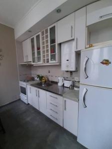a kitchen with white cabinets and a white refrigerator at Apart Boutique Flor de Lis - con cochera- in Santa Fe